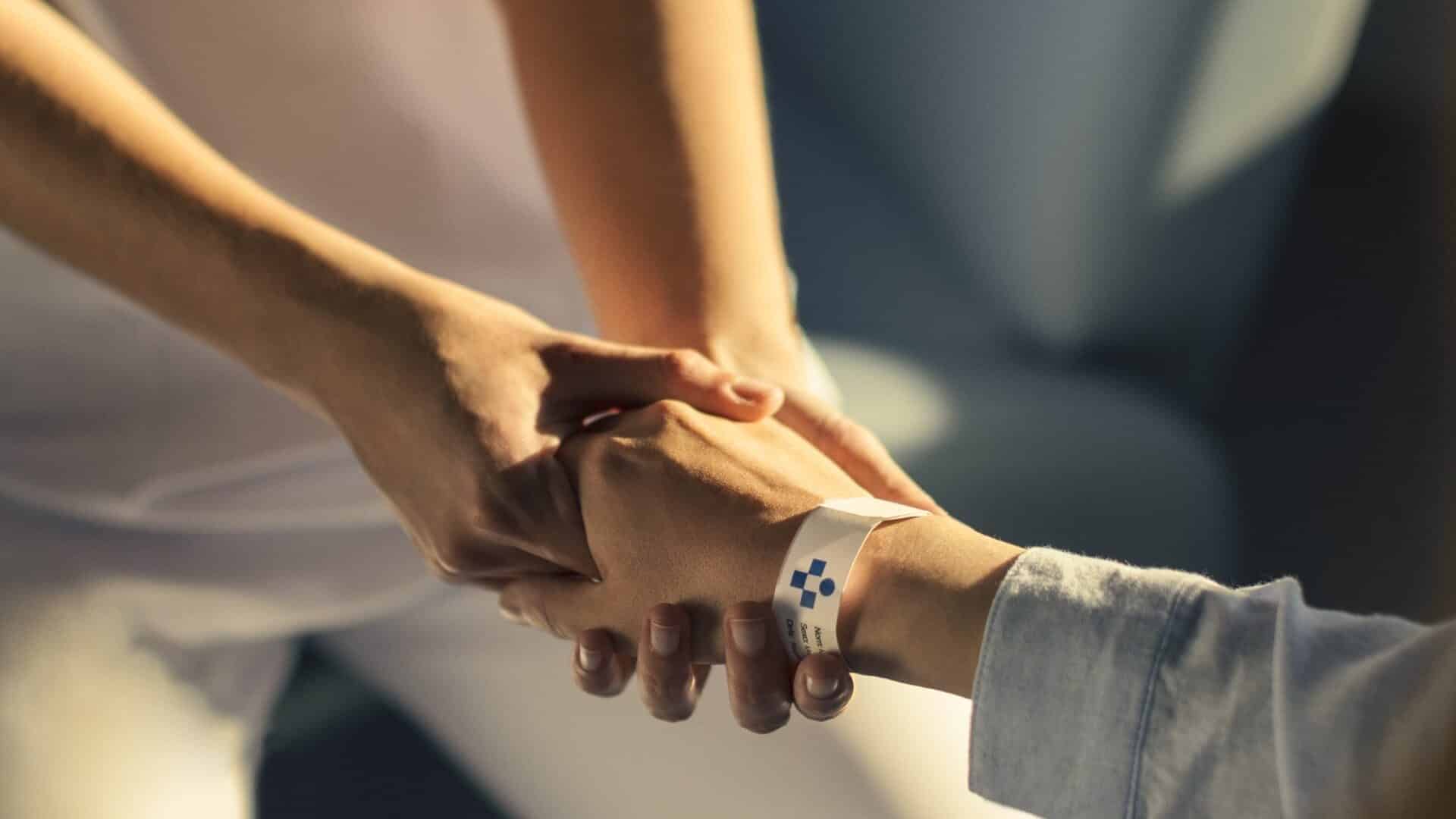 "Curar empieza en cuidar".  Lema de Juaneda Hospitales. Imagen: enfermera sujetando la mano de un paciente.